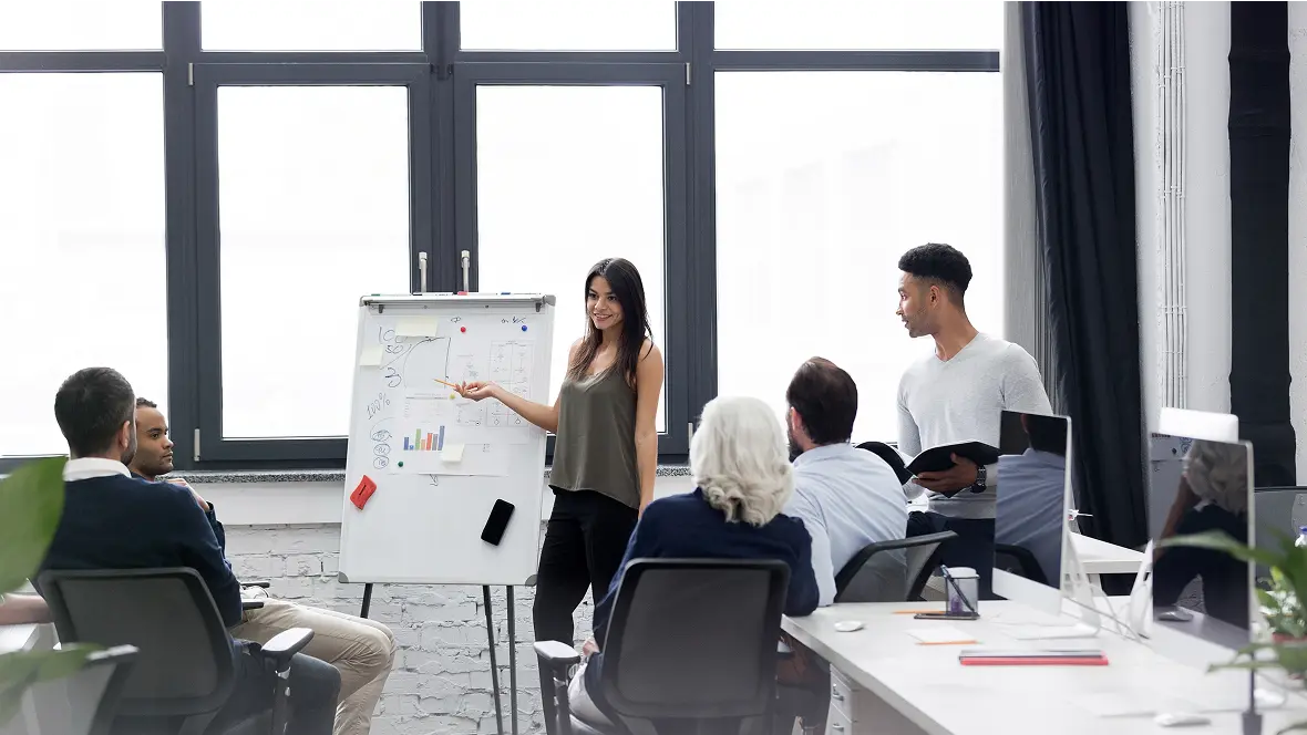 A presenter walking a seated team through a plan on a flip chart