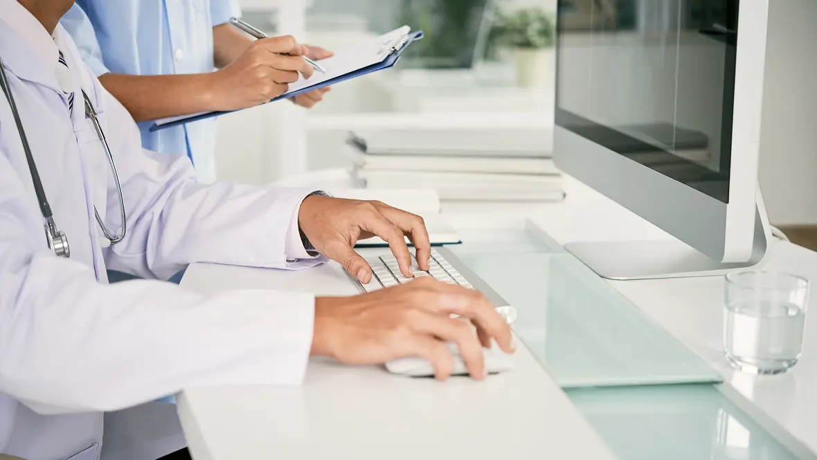 A doctor working at a desktop computer in a clinic